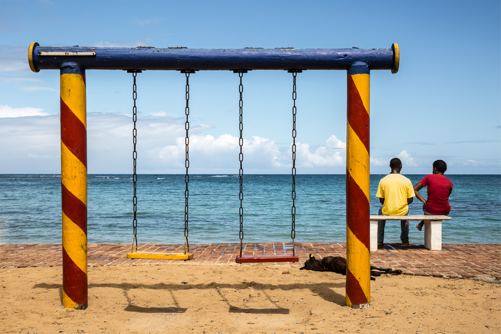 ﻿Two boys sitting next to swing set along the ocean